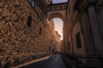 Narrow medieval street between ancient buildings made of rough stone blocks, Florence, Italy