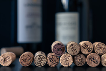 Extracted wine corks with vintage year 2015 to 2020 imprint with two bottles in dark background