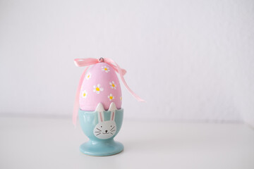 Easter egg in a very cute and funny Easter bunny-shaped container on a soft and bright background.