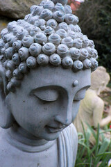 Portrait of a blue gray garden buddha with  another buddha blurred in the background