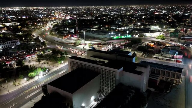 Drone hyperlapse of street intersection with traffic and illuminated buildings at night