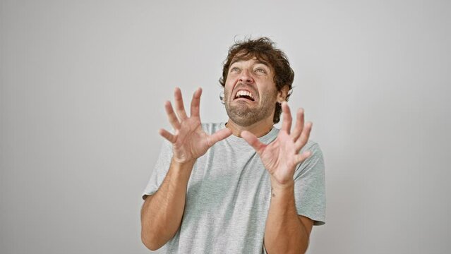 Terrified young man in t-shirt, hands raised in fear, mouth agape in horrified shock. yelling, panic etched on his face against isolated white wall. portrait of raw fear, big no-no concept.