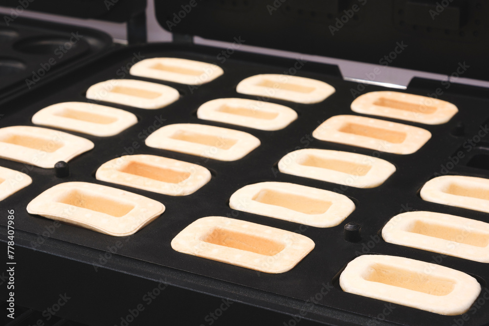 Poster a tray of baked goods with a black background. the baked goods are in the shape of squares and are a