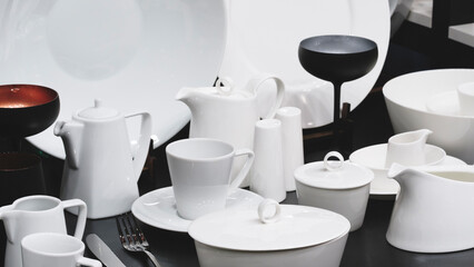 A table with a variety of white dishes and utensils, including a fork, knife, and spoon
