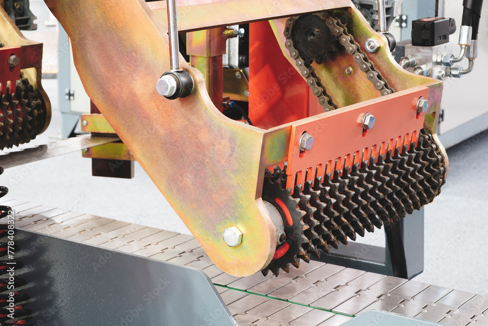 Poster A machine with a chain and a red and orange handle. The chain is made of metal and has a lot of spikes, Industrial woodworking machine