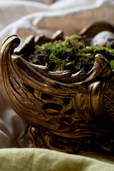 A massive bronze vase on legs with moss, greenery sprouted in an egg. A new life - 778415113