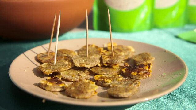 Small Pancakes with Toothpick Sticks on a Plate. Man's Hand Takes One To Taste. A Pancake or Hotcake, Griddlecake, or Flapjack is a Flat Cake, Often Thin and Round, Prepared from Starch-based Batter.