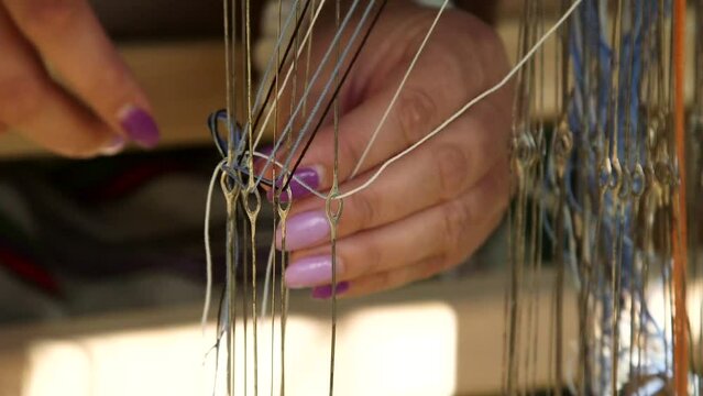 Woman Preparing to Weave on a Loom. Arranging the Threads through Eyelets. Weaving is a Method of Textile Production in Which Two Sets of Yarns are Interlaced to Form a Fabric or Cloth.