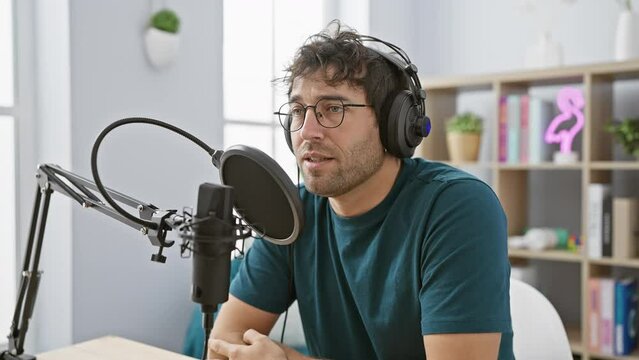 Depressed young hispanic man crying in the radio studio, anger and stress evident in his expression. sadness and distress riddle his worried face as he listens through headphones.