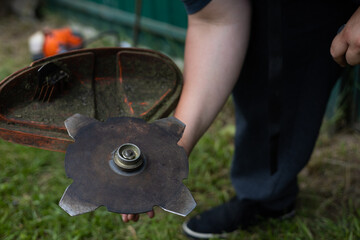 Close-up. Metal disc on a grass trimmer. The man changed the trimmer attachment from a nylon thread...