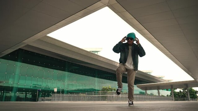 Happy hipster practice b boy dance with stylish cloth at building. Skilled street dancer enjoy show footstep performance. Modern lifestyle, break dancing. Slow motion. Outdoor sport 2024. Sprightly.