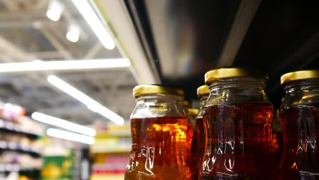 Close-up of many glass bottles of apple juice on a store shelf and a male hand taking one