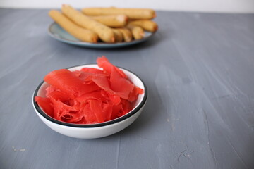 Red pickled ginger on a plate. A spicy oriental seasoning product. Food Additives
