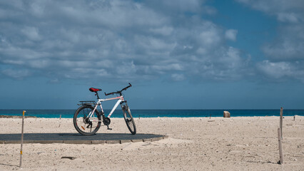 Bicycle stands on a sandy beach opposite sea and sky at background