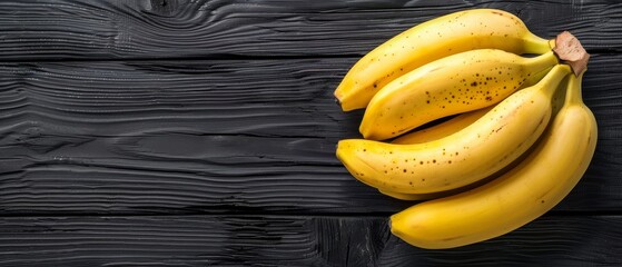   A cluster of yellow bananas resting on a dark wooden surface alongside a sheet of written paper
