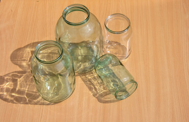 glass jars for preservation of different sizes on a wooden background in sunlight