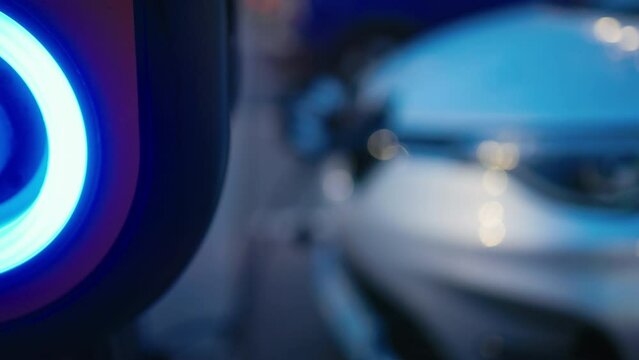 Green mobility: A white electric car charges up at an EV station, exemplifying sustainable transportation practices at a shopping mall parking lot in the evening