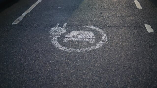 A chalk drawing of an EV charging station on a roadside asphalt surface