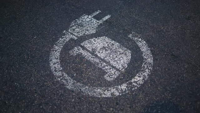 Monochrome chalk art of electric plug on grey asphalt road surface