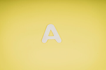 Letter A in wood on yellow background