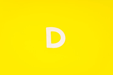 Letter D in wood on yellow background
