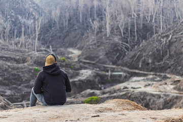 landscape of a lonely man sitting on the slopes of volcano