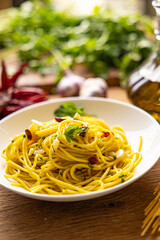 A plate of spaghetti aglio e olio with chili flakes, fresh parsley, garlic, and a drizzle of extra virgin olive oil