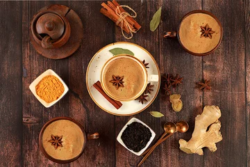 Poster Indian masala chai tea with milk, ginger, anise and cinnamon on an old wooden table. Traditional drink with spices, cafe concept, advertising for restaurant and menu. © Светлана Балынь