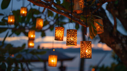 A series of small, gold paper lanterns hanging from a tree branch at dusk, creating a magical and...