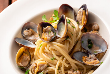 Piatto di deliziosi spaghetti conditi con vongole veraci e prezzemolo, pasta italiana, cibo mediterraneo - 778477733