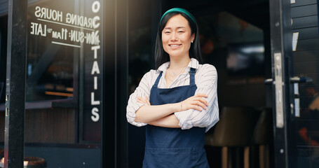 Happy asian woman, cafe and owner by door of small business in confidence for management. Portrait of young female person or waitress smile with arms crossed by professional restaurant or coffee shop