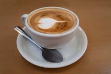 Shallow focus on the bubbles in the froth of a flat white coffee in a white cup and saucer and a...