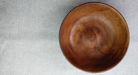 Empty wooden bowl on a linen tablecloth, top view, copy space