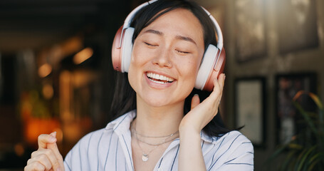 Happy asian woman, headphones and listening to playlist music in cafe for audio streaming, dancing...
