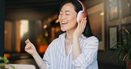 Happy asian woman, headphones and listening to playlist music in cafe for audio streaming, dancing...
