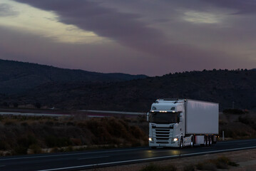 Truck with refrigerated semi-trailer traveling on a highway at dusk, transporting fruits and...