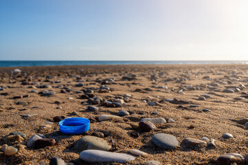 Schraubverschluss einer Trinkflasche am Strand eines Meeres als Symbol für die Verschmutzung der Ozeane durch Mikroplastik
