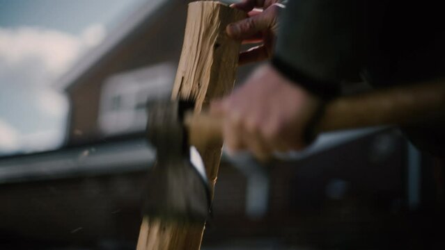 Carpenter man chopping wood with axe, carving the wood into a cross, using traditional techniques all by hand. 