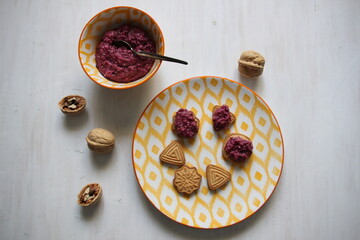 sweet urbech dessert made of nuts with berries in a bowl on wooden table with cookies