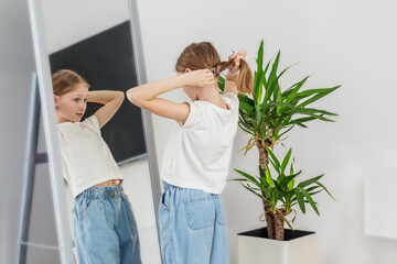 Child Girl Tying Hair in Front of Mirror. Morning preparation before school.