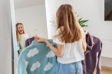 Laughing Child with Sweaters, Fun Wardrobe Choices. Morning preparation before school.