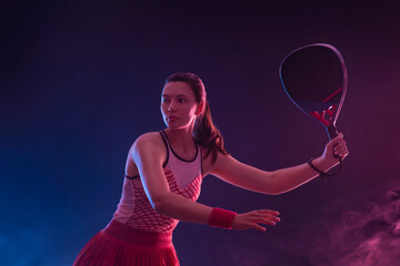 Padel tennis player with racket on tournament. Girl athlete with paddle racket on court with neon colors. Sport concept. Download a high quality photo for design of a sports app or tour events. - 778499147