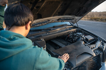 the man has opened the hood of his damaged car and is checking it. stock photo