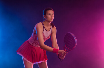 Padel tennis player with racket on tournament. Girl athlete with paddle racket on court with neon colors. Sport concept. Download a high quality photo for design of a sports app or tour events. - 778499514