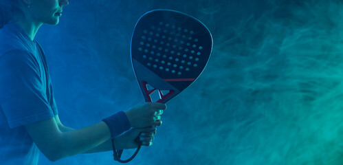 Close-up photo of padel tennis player with racket on tournament. Girl athlete with paddle racket on court with neon colors. Sport concept. No face. - 778500779