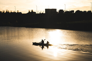 father and daughter kayaking on the river at sunset