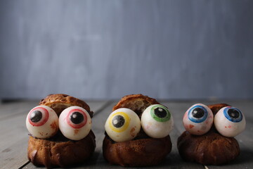 Cakes eclairs with eyes on a gray background with space for copyspace text. Cooking for Halloween. Funny Scary Food