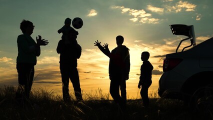 Dad with child son, mother, children play with ball, toy plane, next to car, beautiful sunset. Happy family travels by car. Parents, children stopped at campsite by car. Travelling by car, Family play