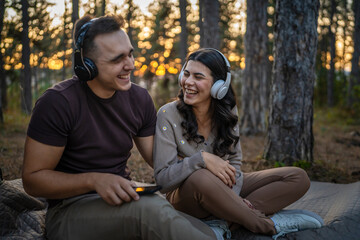 Man and woman young adult couple in nature listen music headphones