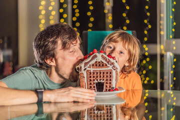 Savor unique moments as dad and son bite into an unconventional gingerbread house, adding a twist to Christmas traditions. A tasty blend of creativity and family joy